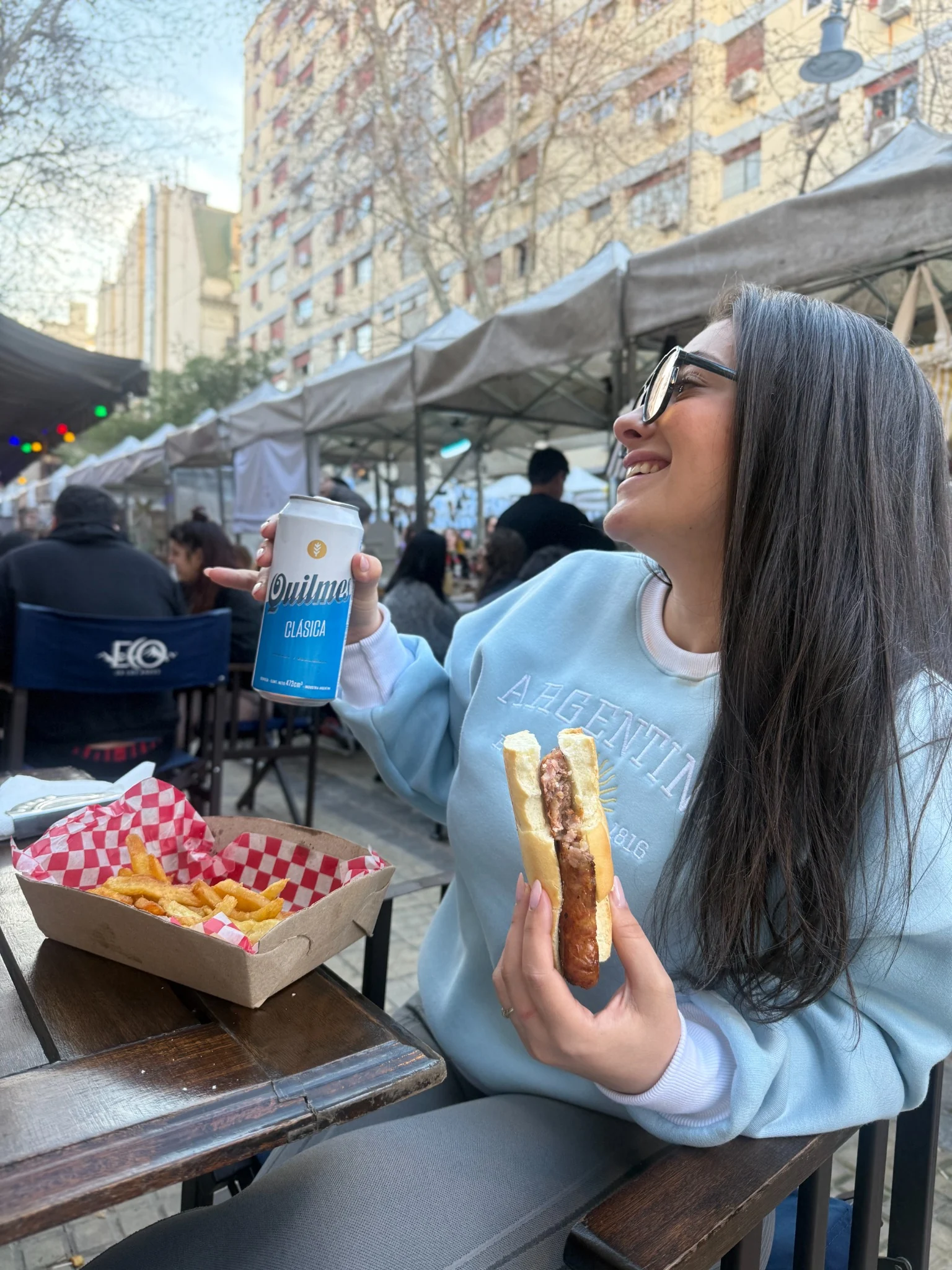 Milena ao ar livre segurando uma bebida e um lanche